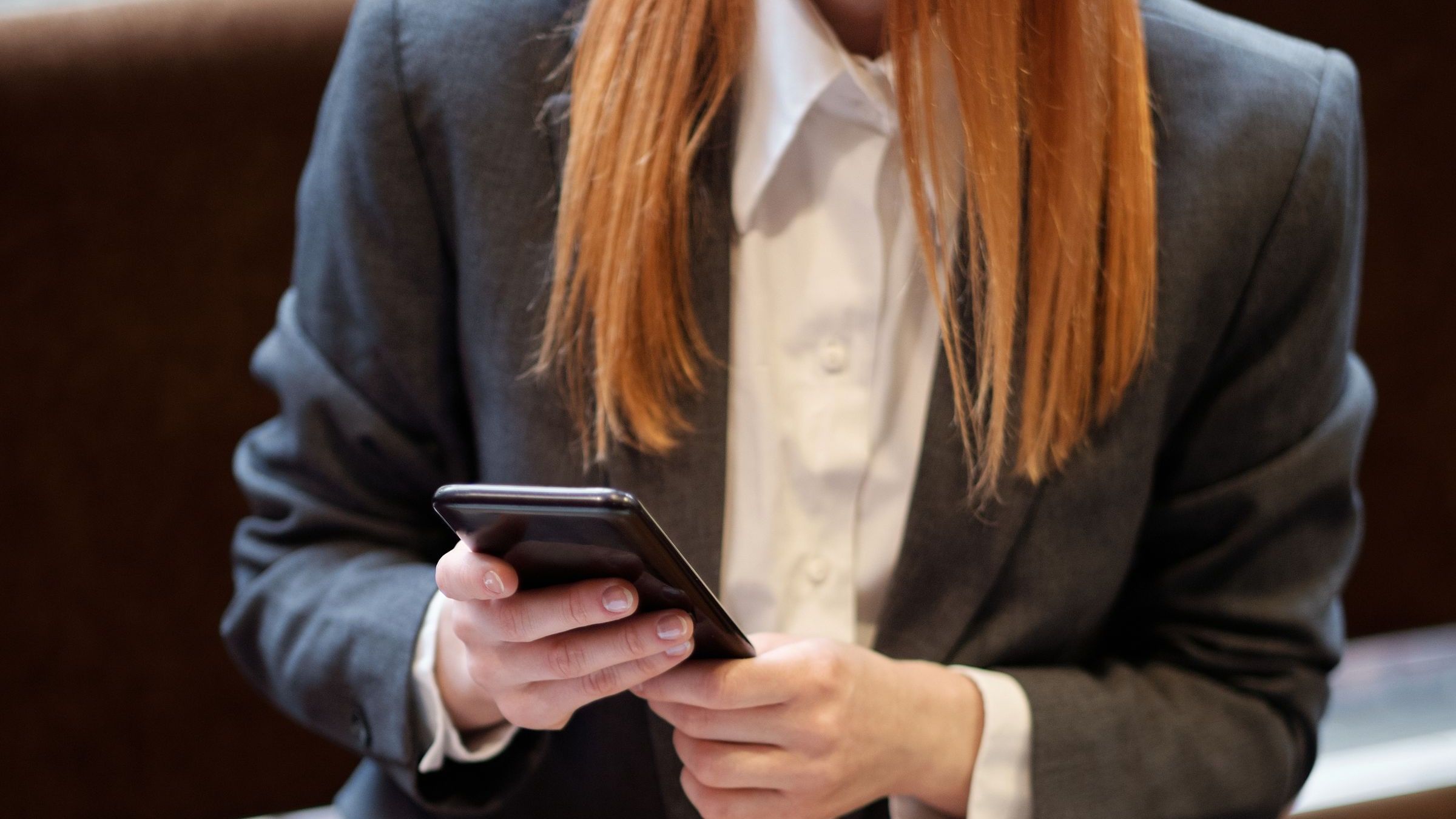 A person holding a smartphone while seated indoors