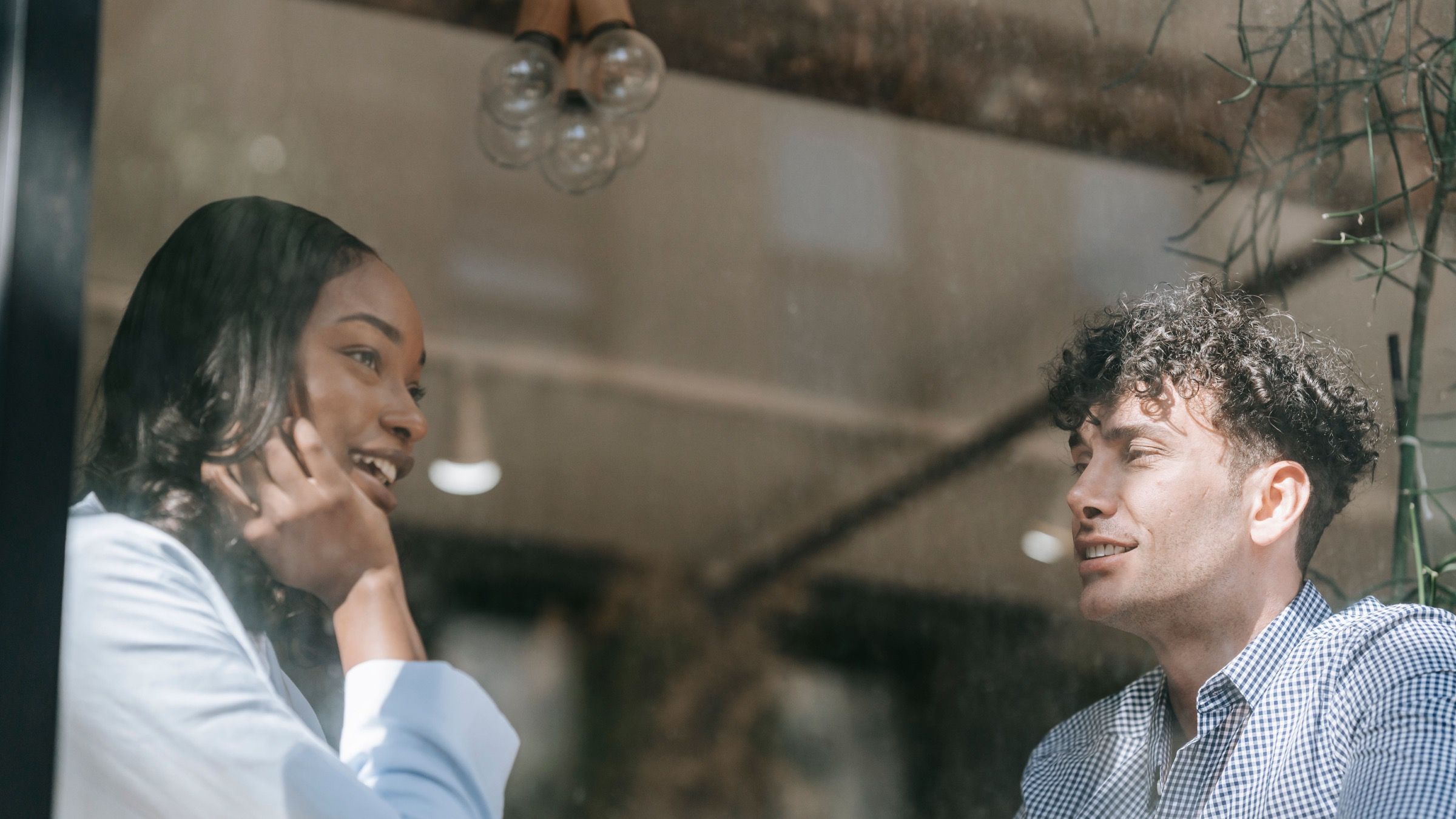Two people talking in a café, seen through a window in natural light